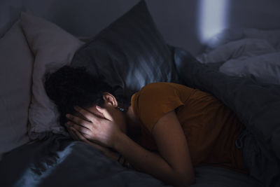 Crying young woman lying in bed