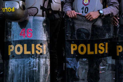 Midsection of police holding shield with text