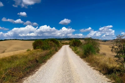 Road amidst field against sky