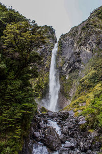 Low angle view of waterfall on rocks against sky