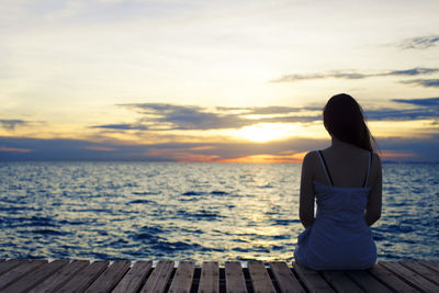 Rear view of a pier in calm sea at sunset