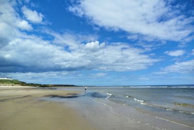 Scenic view of beach against cloudy sky