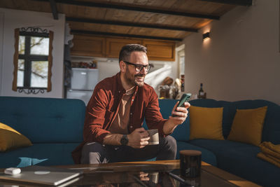 Young man using mobile phone while sitting at home