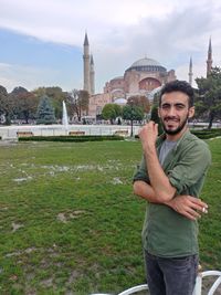 Portrait of smiling young man standing in front of buildings