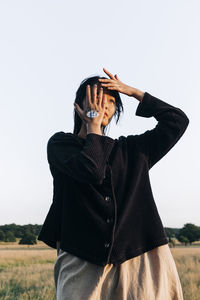 Woman covering eyes with hand standing at park