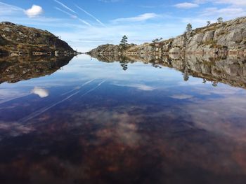 Reflection of rocks in lake against sky