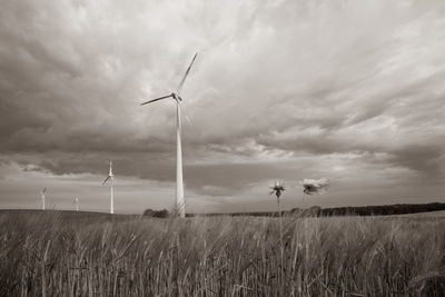 Wind turbines on field against sky