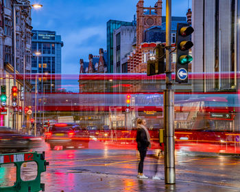 Blurred motion of man walking on illuminated city street