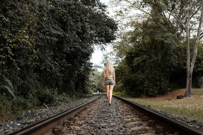 Rear view of man walking on railroad track