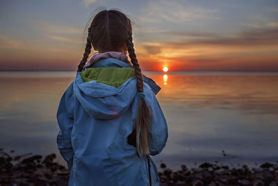 Woman standing on beach against sky during sunset