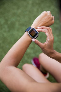 High angle view of female athlete using smart watch while sitting on grassy field