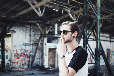 Portrait of young man standing against built structure