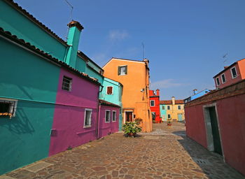 Street amidst buildings in town against blue sky