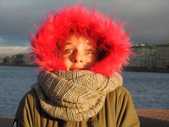 Portrait of girl in red fur coat against lake