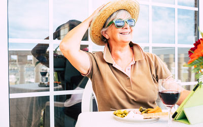 Smiling senior woman with drink and snack at table in restaurant
