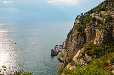 Scenic view of sea by cliff against sky