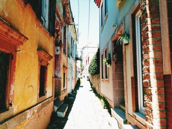 Alley amidst houses against sky
