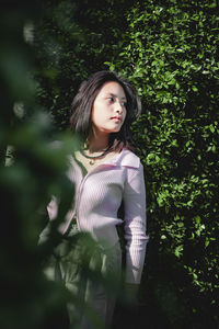 Portrait of woman standing against tree