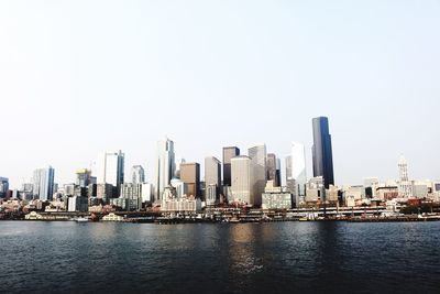 River by cityscape against clear sky