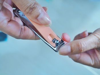 Cropped hands of woman cutting nails with clipper