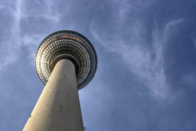 Low angle view of communications tower against cloudy sky