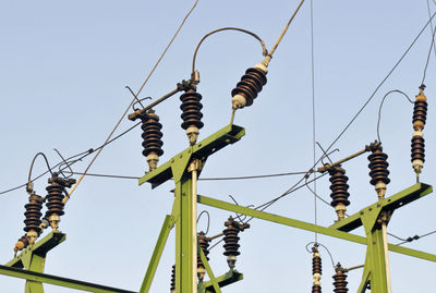 Low angle view of electricity pylon against clear sky