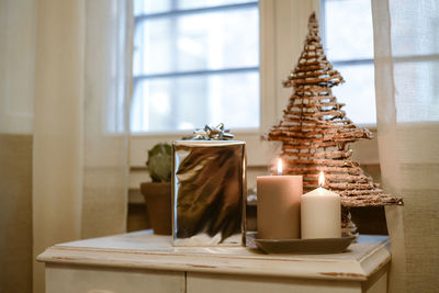 Gift boxes near lighted candles and christmas tree inside home. box with holiday ribbon with bows 