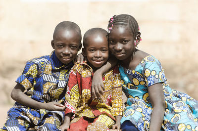 Portrait of smiling siblings sitting outdoors