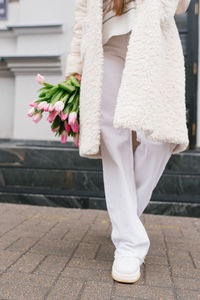 Bouquet of tulips in a woman's hand and white pants in red close-up