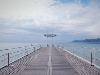 Pier on sea against cloudy sky