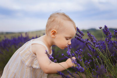 Side view of girl looking away while standing against sky