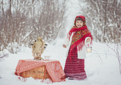 Portrait of smiling young woman standing against snow covered field