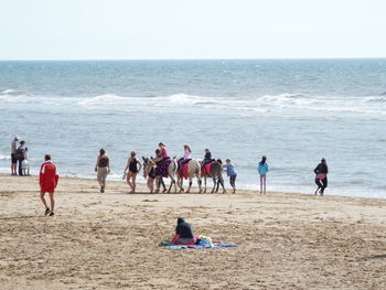 People at beach against clear sky