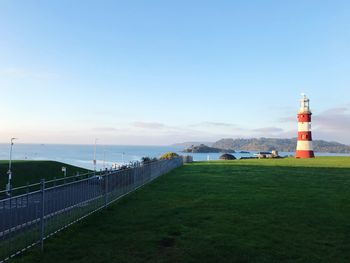 Lighthouse by sea against sky