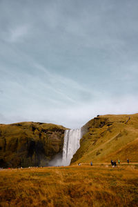 Scenic view of waterfall on land against sky