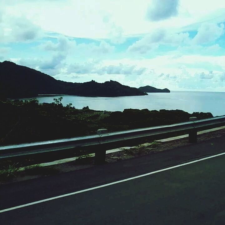 sky, mountain, tranquil scene, scenics, tranquility, cloud - sky, water, beauty in nature, sea, nature, cloud, mountain range, landscape, road, cloudy, railing, idyllic, outdoors, no people, remote