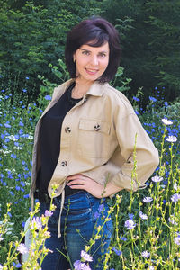 Portrait of young woman standing amidst plants