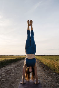 Full length of woman on road amidst field against sky