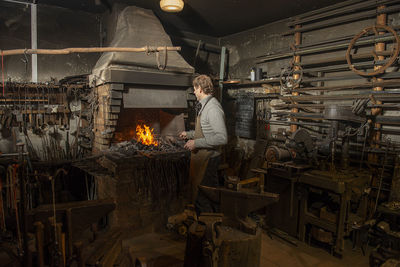 Blacksmith heating metal rod in fire