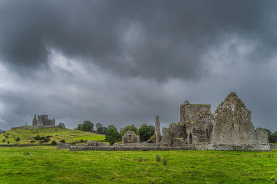 Old ruins of building on field against cloudy sky