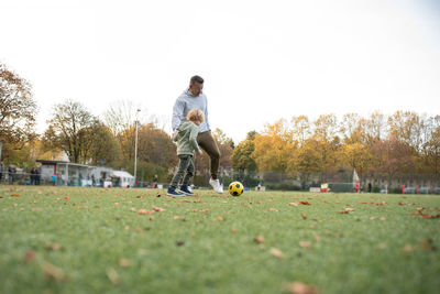 A little boy plays soccer with his father on the soccer field