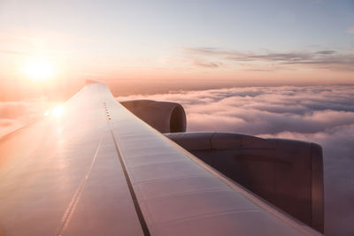 Airplane wing against sky during sunset