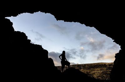 Silhouette woman standing at cave in fuerteventura against sky