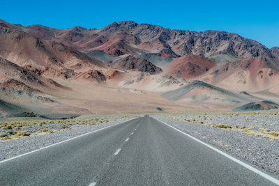 Road leading towards mountains against sky