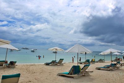 Lounge chairs and parasols on beach against sky