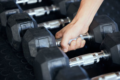 Midsection of man lifting dumbbell in gym