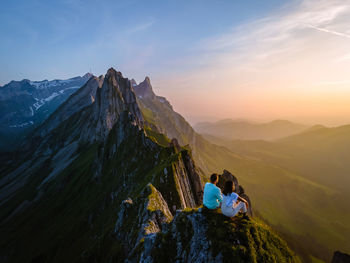 Rear view of people on mountain against sky during sunset