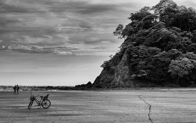 Bicycle parked at beach against sky