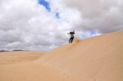 Low angle view of person standing on mountain against cloudy sky