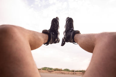 Low section of man wearing roller skates against sky